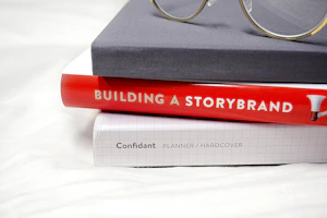 Stack of bestselling business books with a pair of reading glasses on top