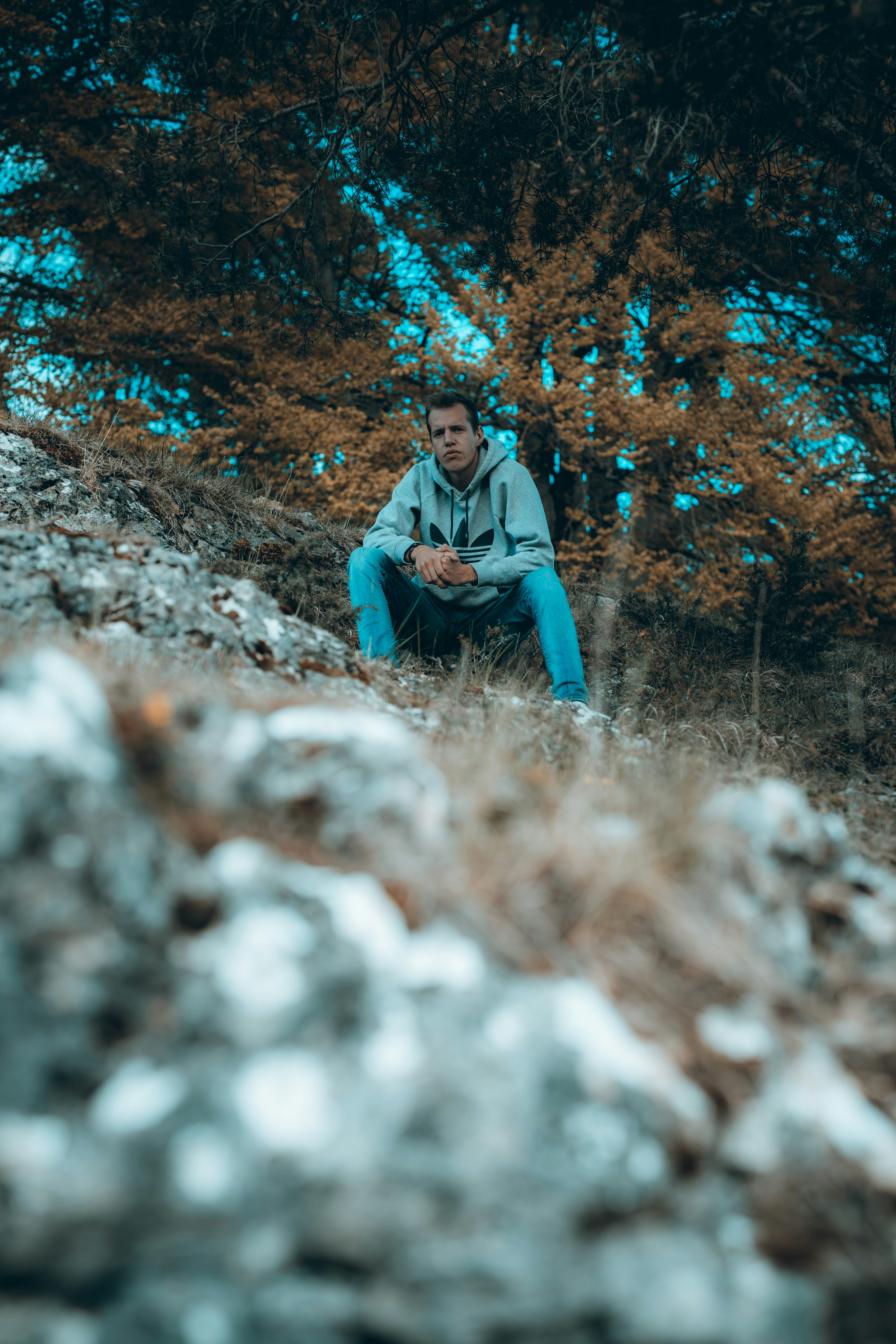 woman in gray hoodie sitting on gray rock