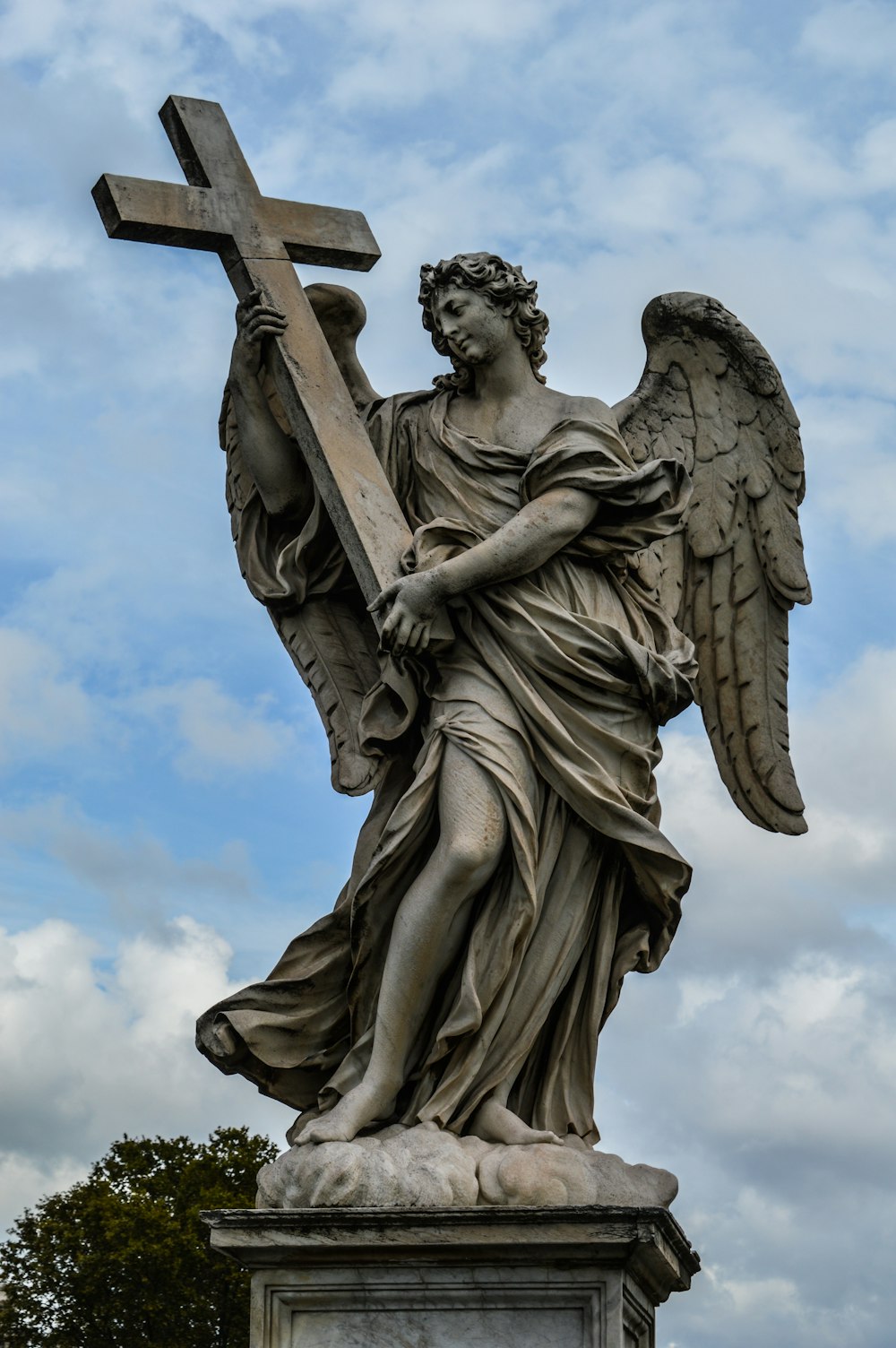 Estatua de ángel bajo nubes blancas durante el día