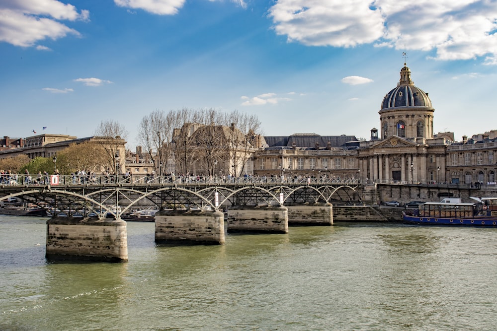 Edificio in cemento marrone vicino al ponte e al fiume sotto il cielo blu durante il giorno