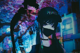 A dimly lit scene featuring a person wearing a colorful hoodie and a mask, with projections of neon lights and urban imagery. Next to them is an anime-style figure, also masked and wearing a cap with a word on it. The background is filled with blue and purple tones, displaying blurred buildings and signage.