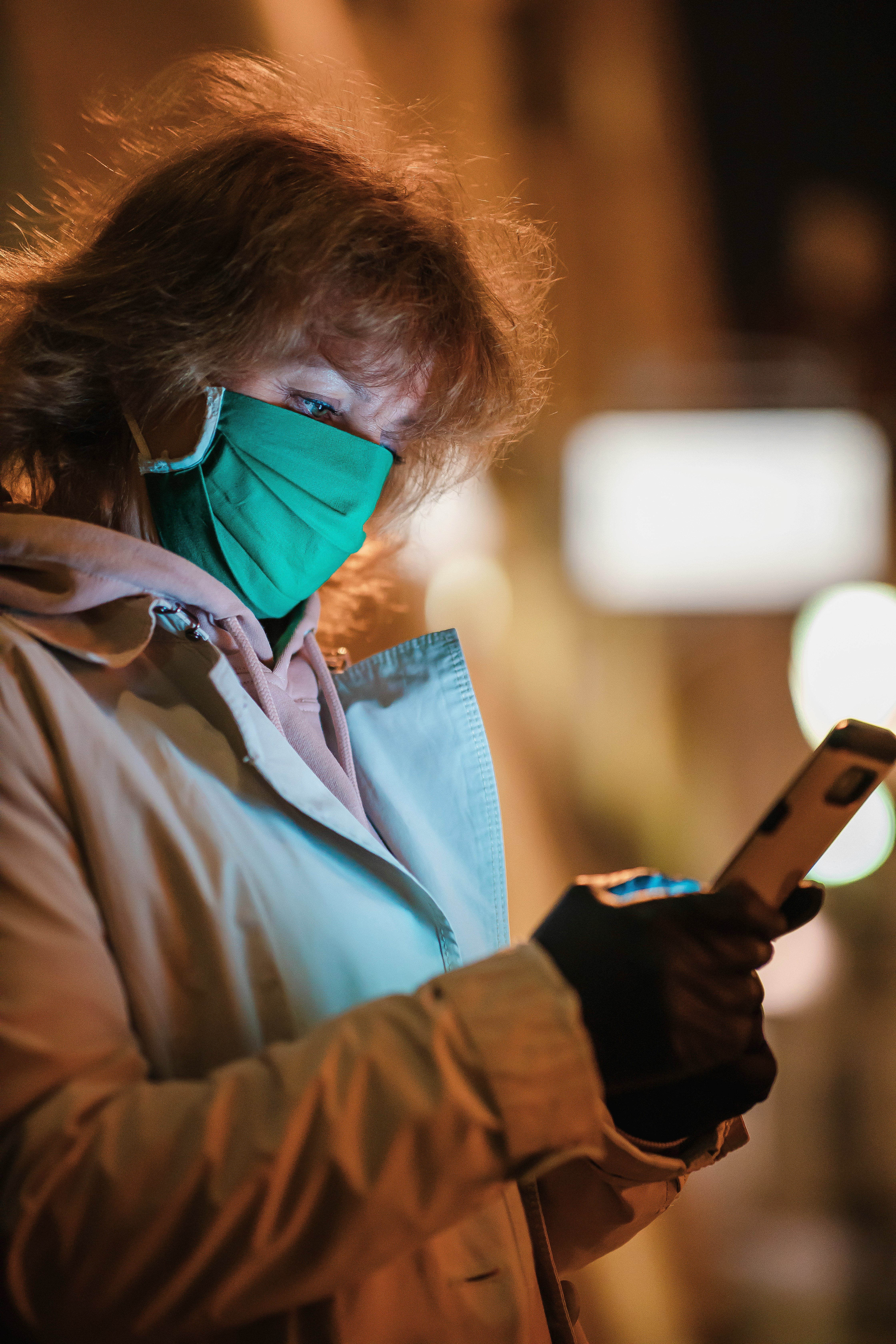 man in brown jacket holding smartphone