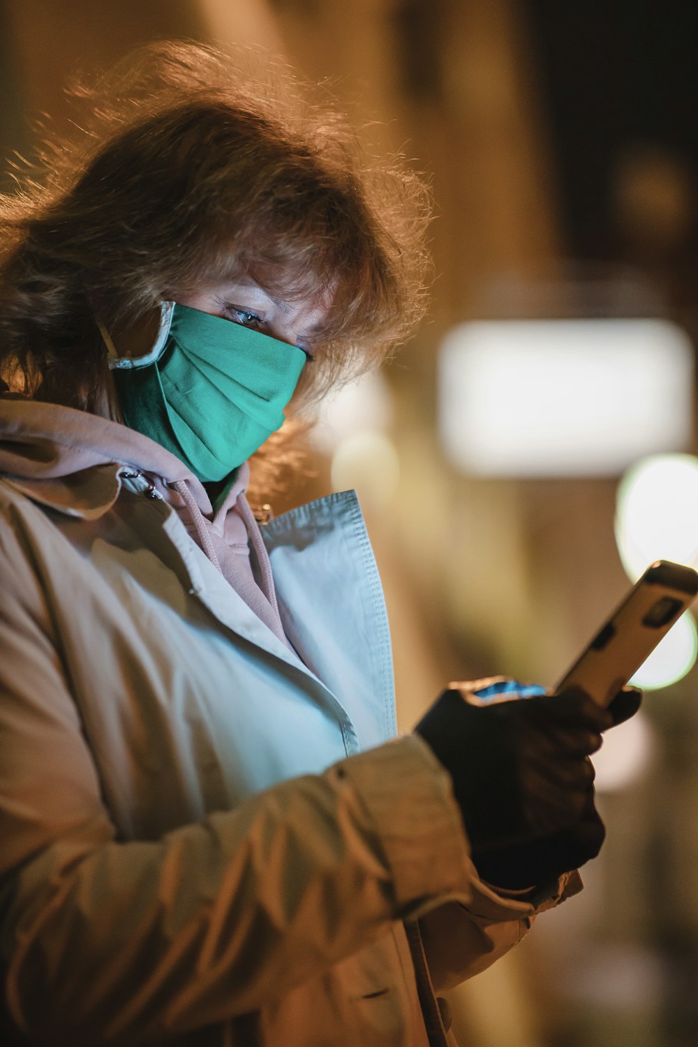 man in brown jacket holding smartphone