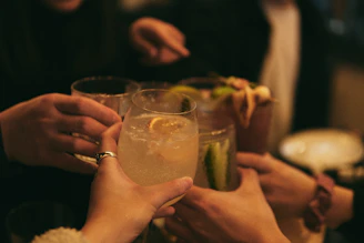 A close-up of hands clinking whiskey glasses in a friendly toast, symbolizing partnership and community.