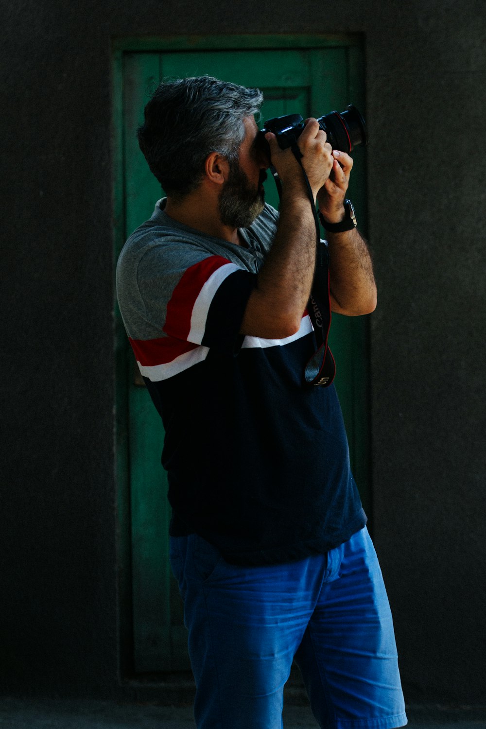 man in blue white and red crew neck t-shirt holding black smartphone