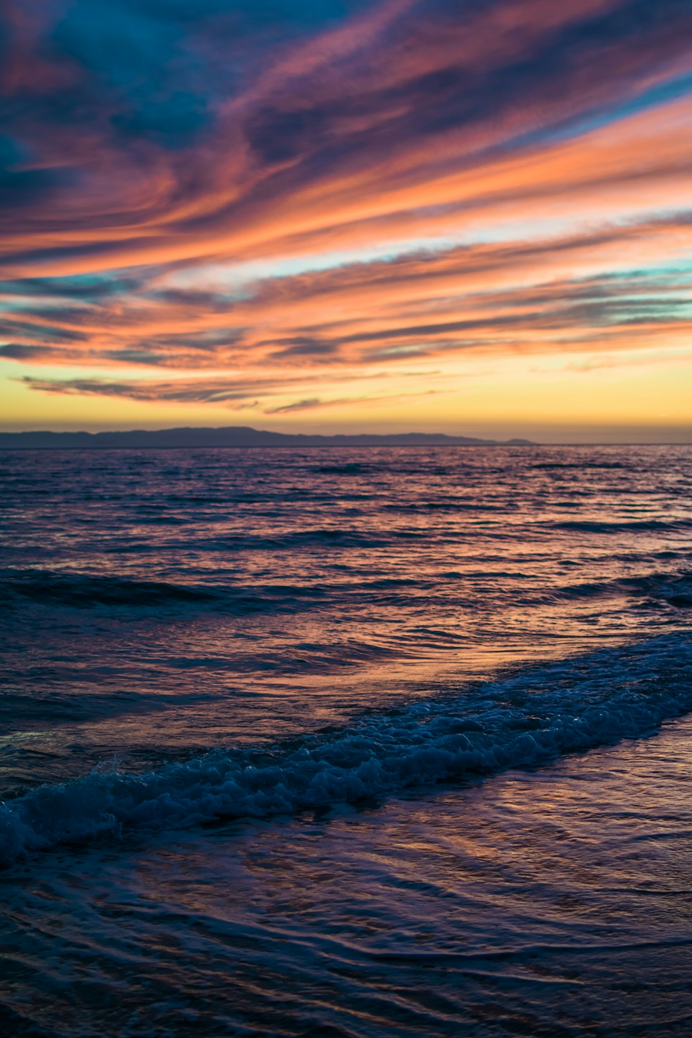 ocean waves crashing on shore during sunset