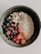 A bowl of creamy oatmeal ice cream topped with fresh berries and nuts.