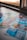 A selection of colorful lottery scratch-off tickets placed on a flat surface near a window. The image has a shallow depth of field, focusing on the tickets while blurring the background. The tickets display various games and prize amounts.