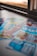 A selection of colorful lottery scratch-off tickets placed on a flat surface near a window. The image has a shallow depth of field, focusing on the tickets while blurring the background. The tickets display various games and prize amounts.