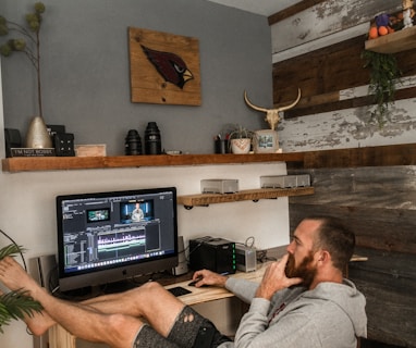 man in gray shirt and black shorts sitting on chair using laptop computer