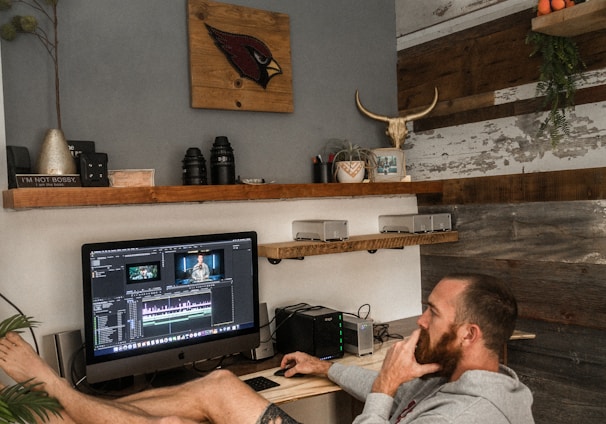 man in gray shirt and black shorts sitting on chair using laptop computer