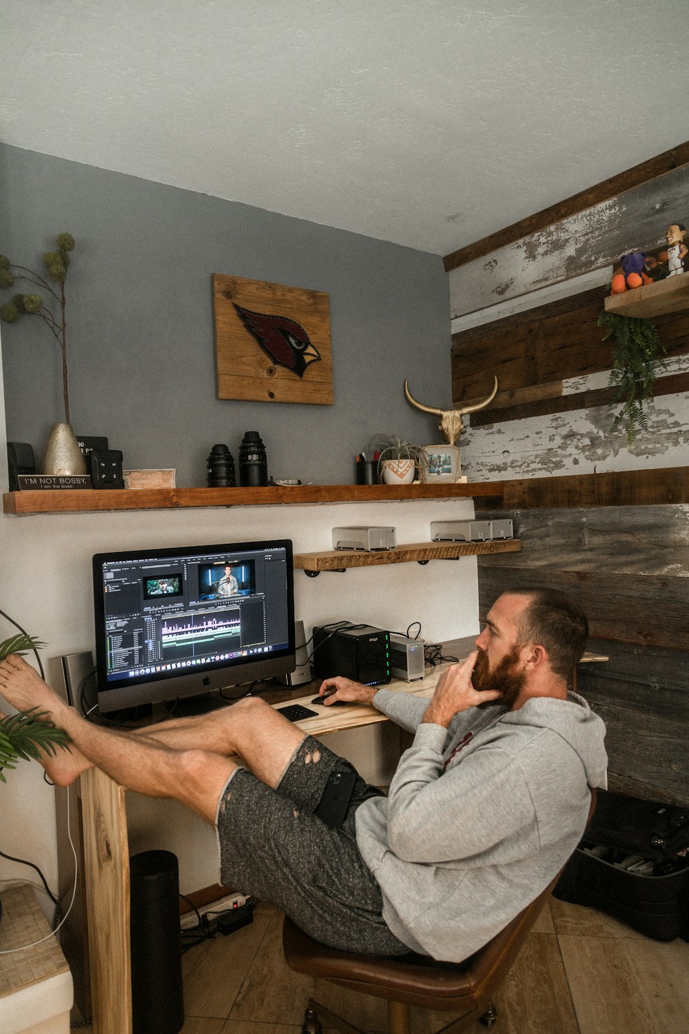 Hombre con camisa gris y pantalones cortos negros sentado en la silla usando una computadora portátil