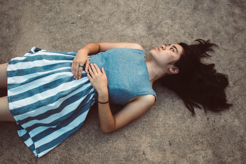 woman in blue tank top lying on gray carpet