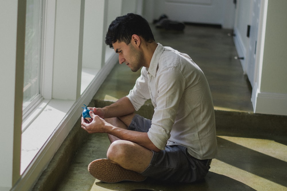 man in white dress shirt and black pants sitting on floor