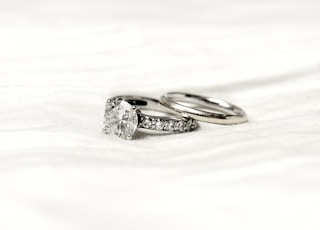 silver diamond ring on white textile