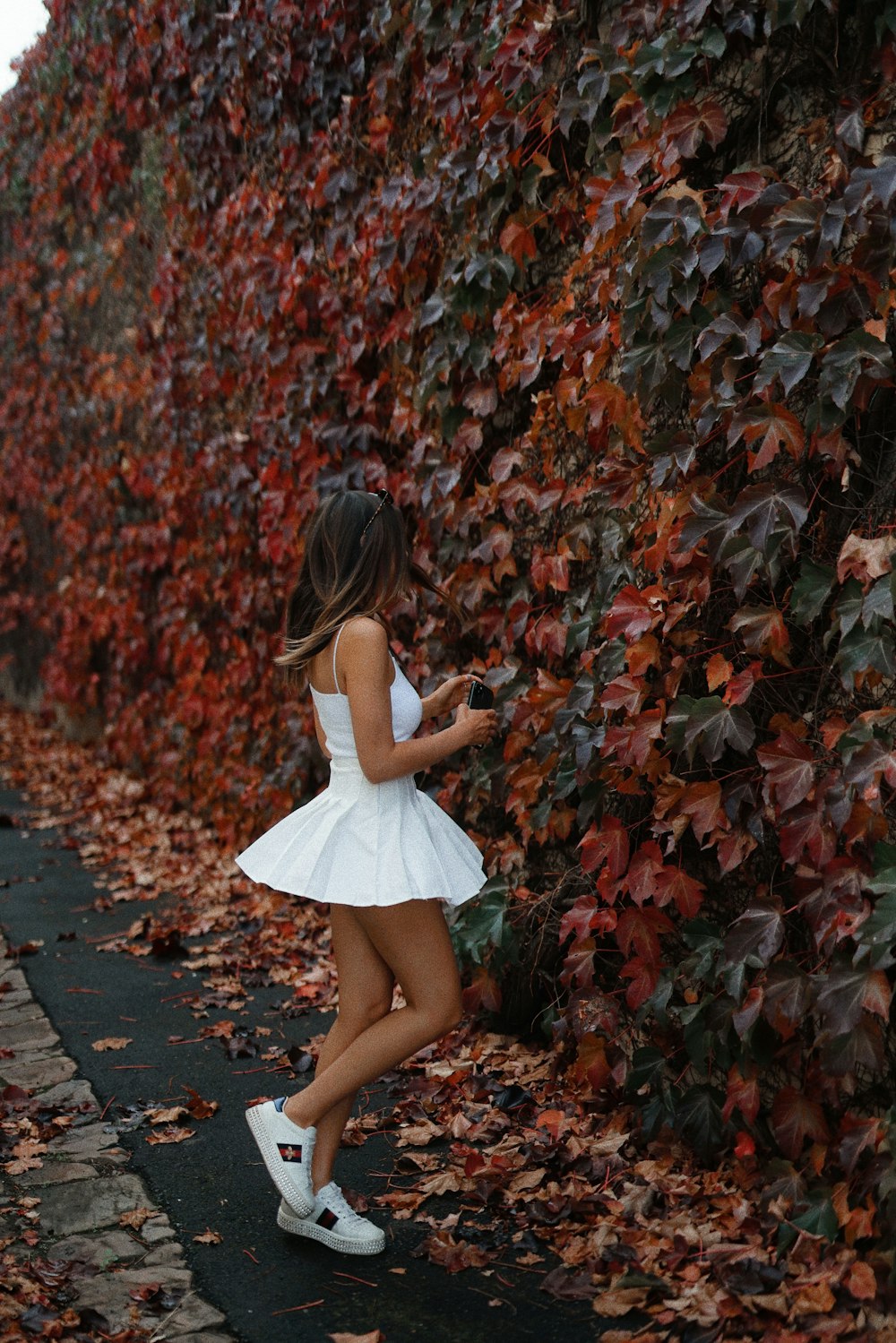 woman in white mini dress standing on red leaves