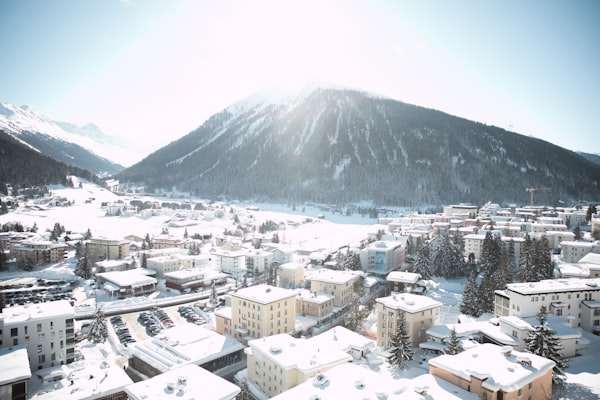 Aerial view of snow-covered Davos spread along its wide valley floor beneath a sunlit mountain