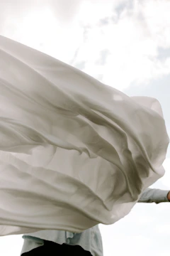 Soft fabric flowing gracefully in a warm breeze against a clear sky