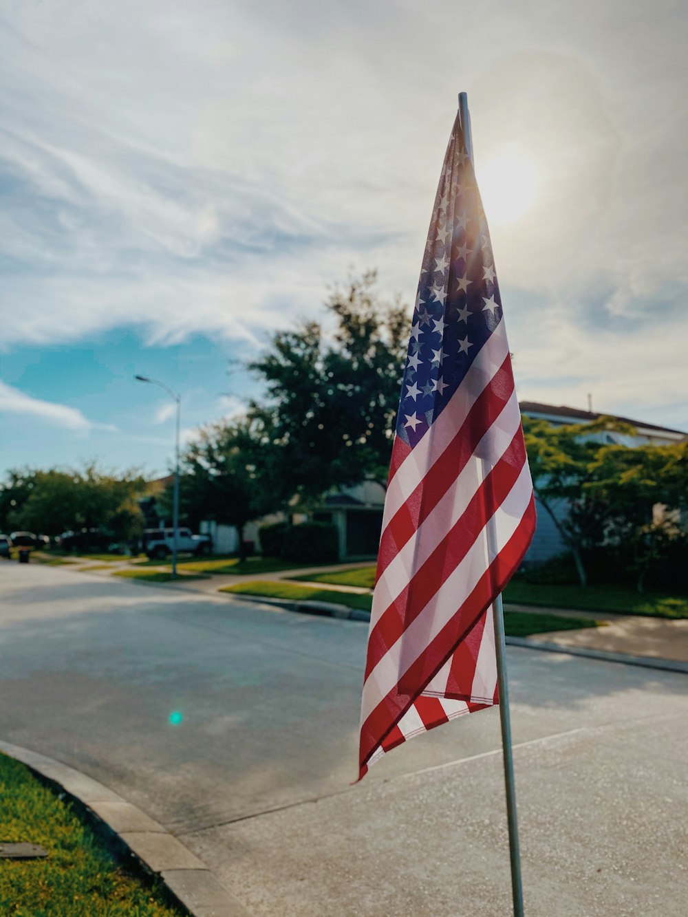 日中の灰色のアスファルト道路に国旗を掲げる米国