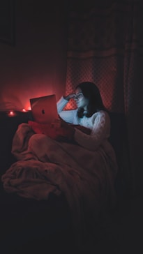 woman sitting in the dark looking. at a computer screen doing online somatic therapy