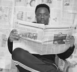 woman in black and white long sleeve shirt holding newspaper
