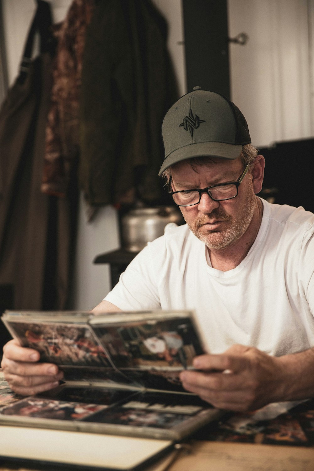 man in white crew neck t-shirt holding white and black book