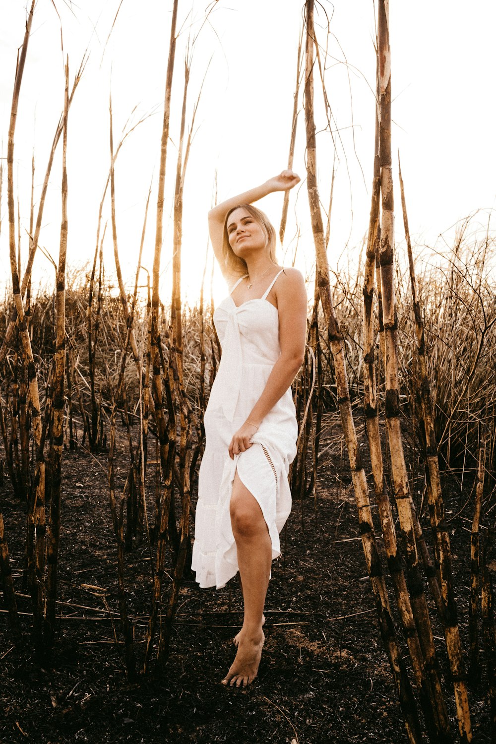 woman in white spaghetti strap dress standing on brown grass field