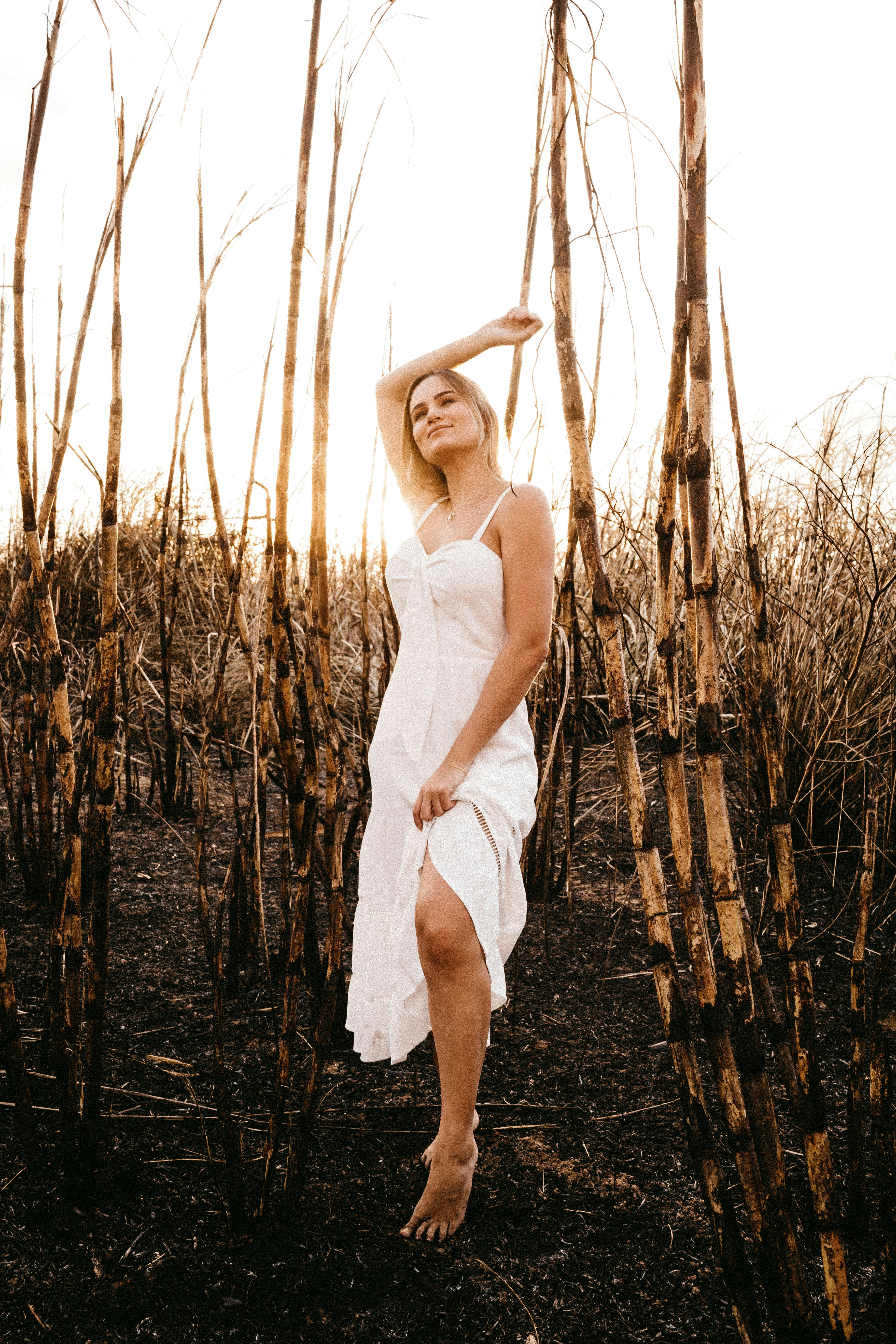 woman in white spaghetti strap dress standing on brown grass field