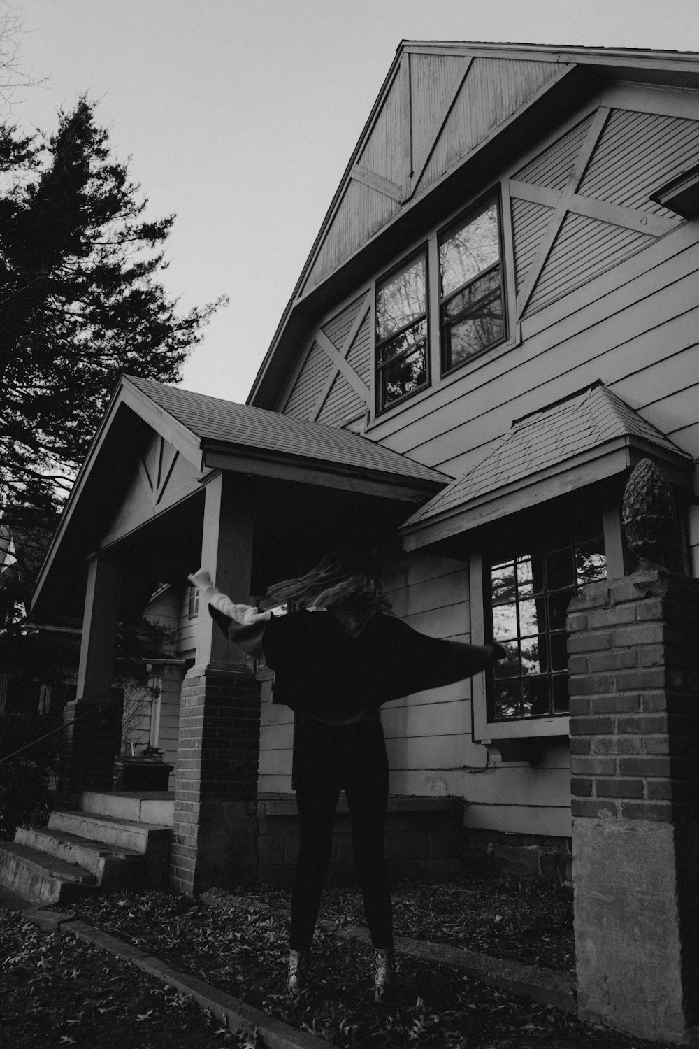 man in black t-shirt and black pants standing near house