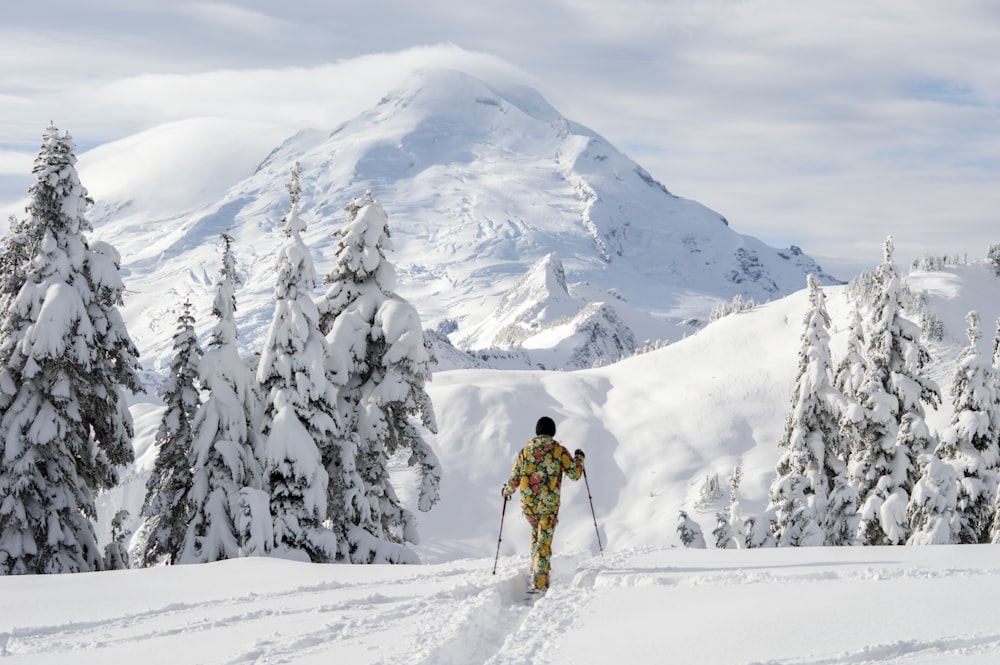 person in yellow jacket and black pants standing on snow covered ground during daytime