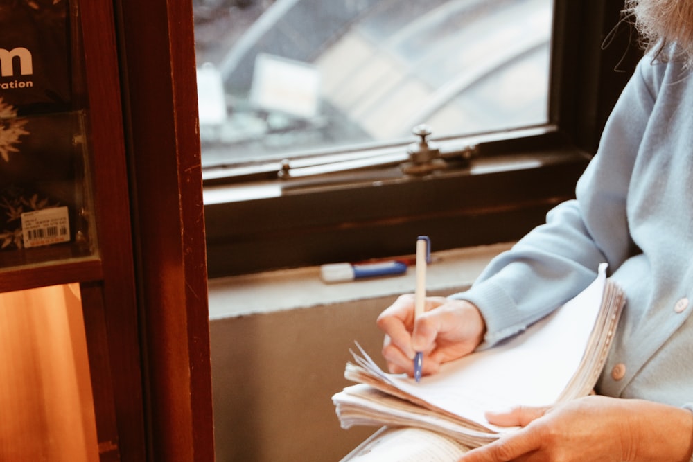 person in white long sleeve shirt holding white pen