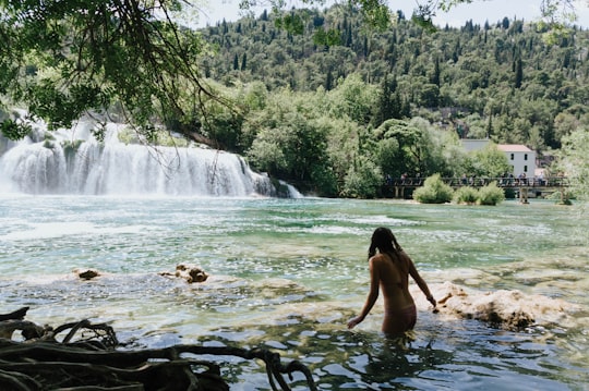 woman in black bikini standing on water falls during daytime in Krka National Park Croatia