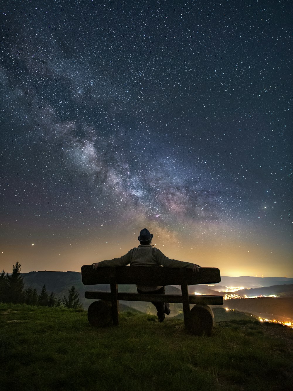 homme et femme assis sur un banc sous la nuit étoilée
