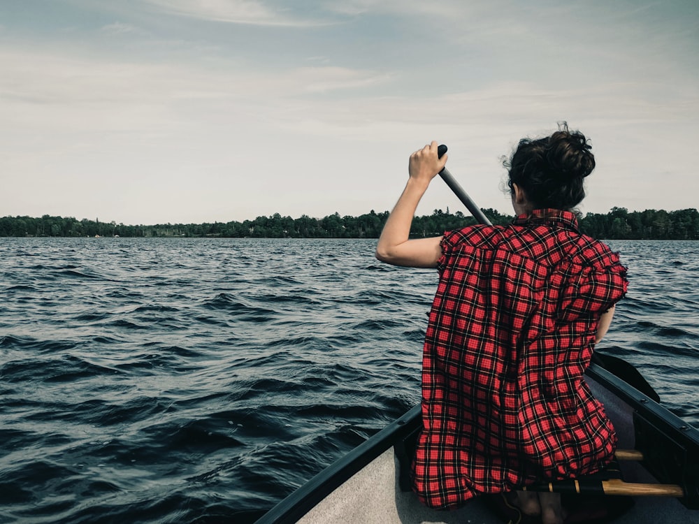 man in red and black plaid shirt sitting on boat during daytime