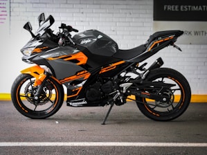black and orange sports bike parked beside white wall