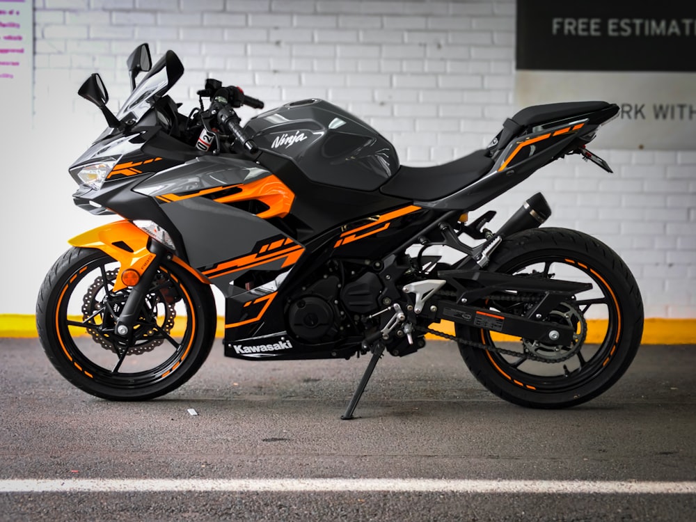 black and orange sports bike parked beside white wall