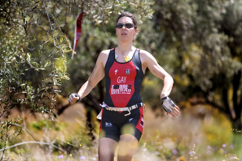 Femme en débardeur rouge courant sur le terrain pendant la journée