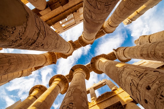 low angle photography of brown concrete building under blue sky during daytime in Luxor Egypt