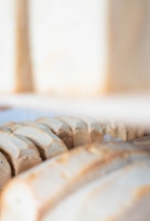 Artisan breads lined up in a neat row against a soft beige backdrop, highlighting their warm crusts