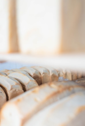 Artisan breads lined up in a neat row against a soft beige backdrop, highlighting their warm crusts