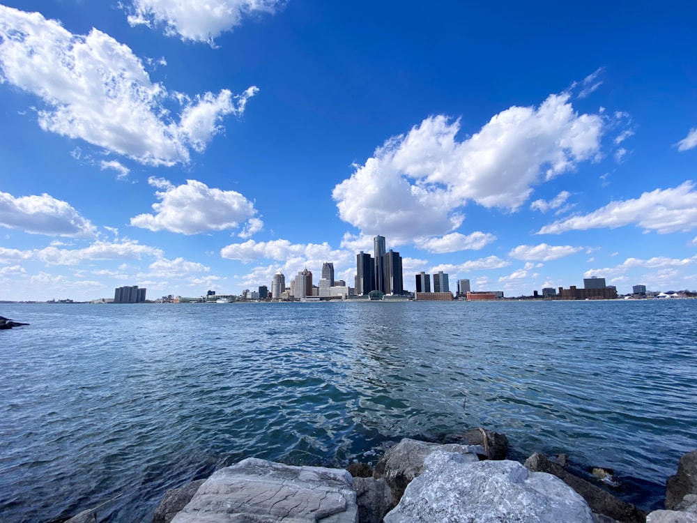 city skyline across body of water under blue and white sunny cloudy sky during daytime