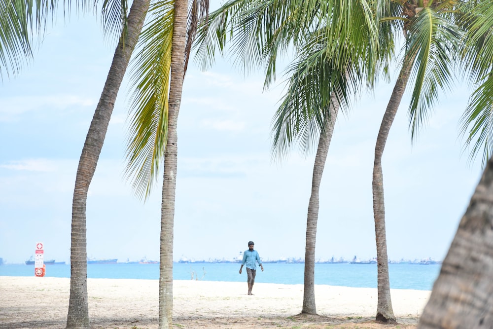 woman in blue dress walking on beach during daytime