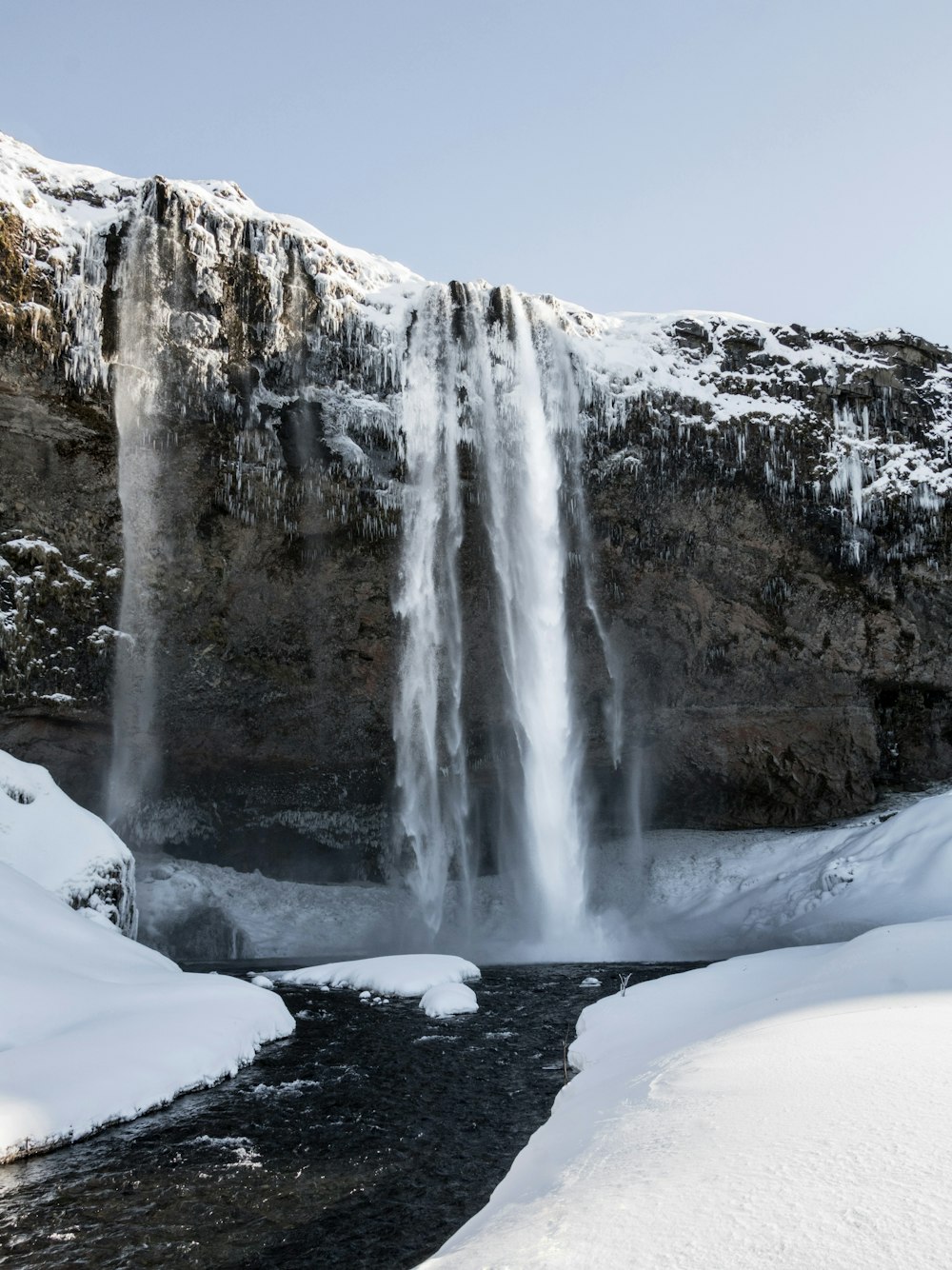 waterfalls on snow covered ground during daytime