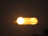 A bright, circular light source appears doubled with motion blur against a dark background, creating a mysterious and dynamic visual effect.