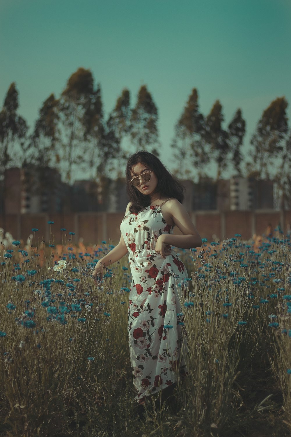 woman in white and blue floral dress standing on flower field during daytime