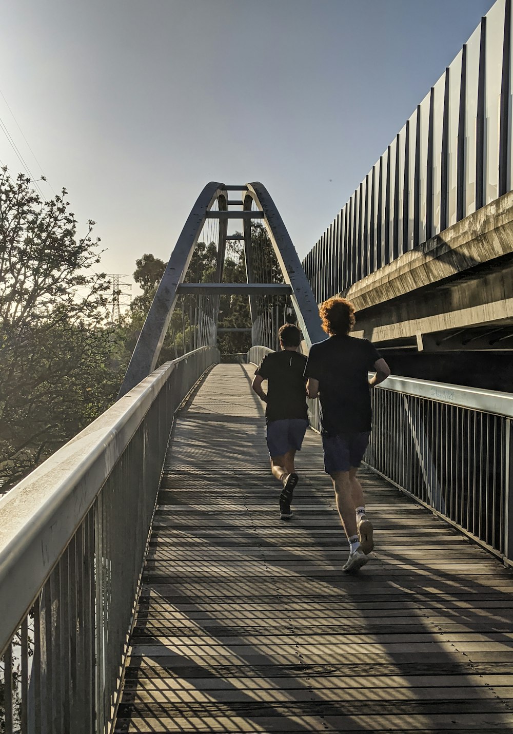 man in black t-shirt and black shorts walking on bridge during daytime