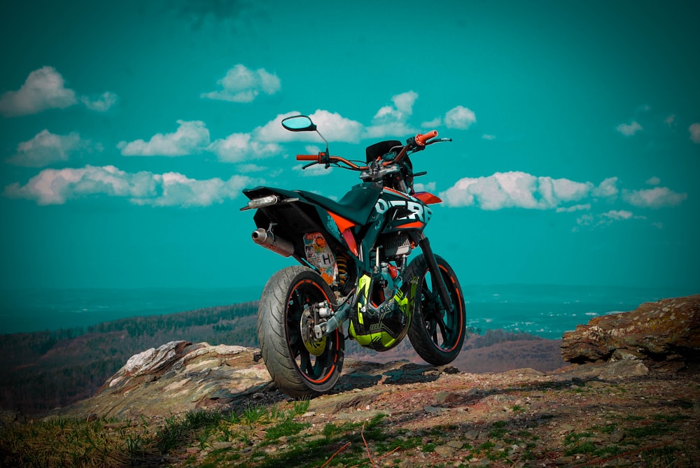 blue and black dirt bike on brown rock near body of water during daytime