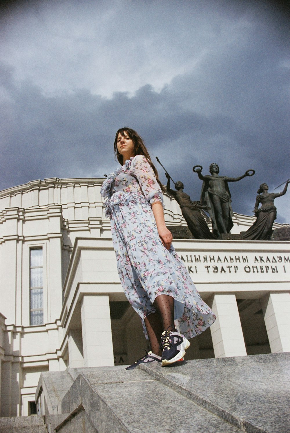 woman in white and blue floral dress standing near statue during daytime