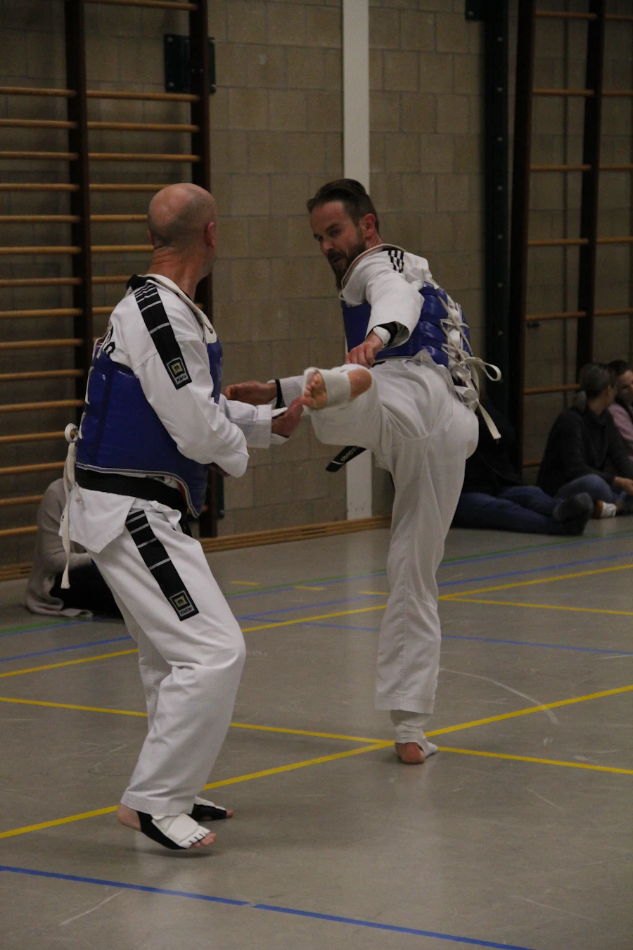 Two athletes in chest protectors sparring in a gym