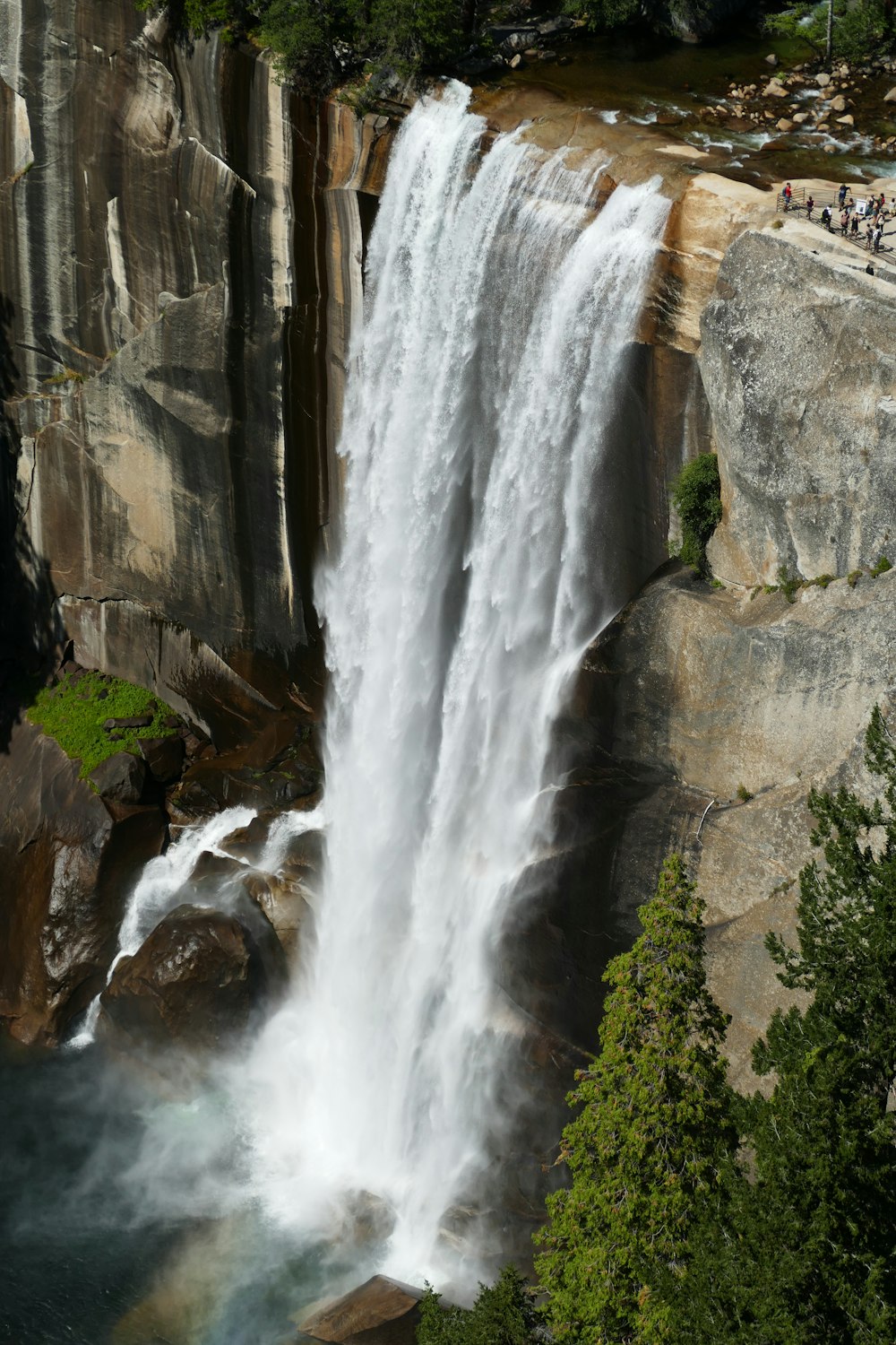 waterfalls in between green trees during daytime